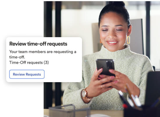 Manager using a smartphone to review and approve employee time-off requests in the ADP mobile app.